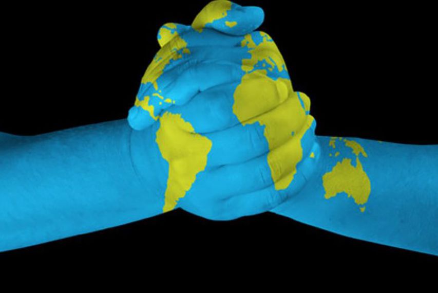 two hands shaking with the image of the world map overlayed